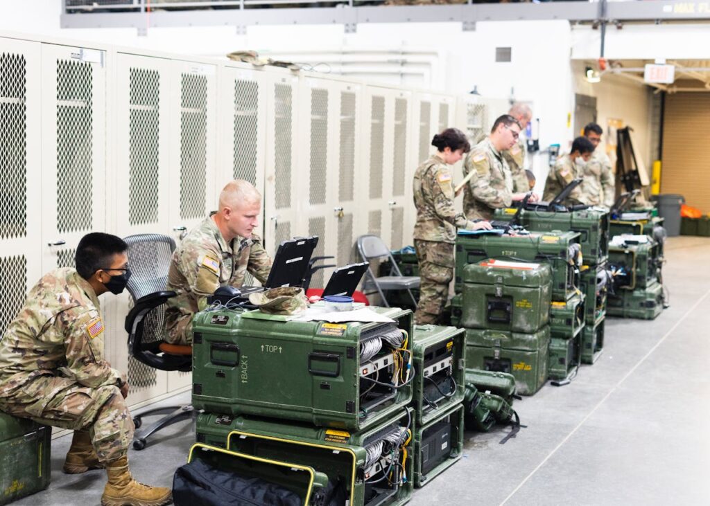 Soldiers sitting beside containers and using computers. 