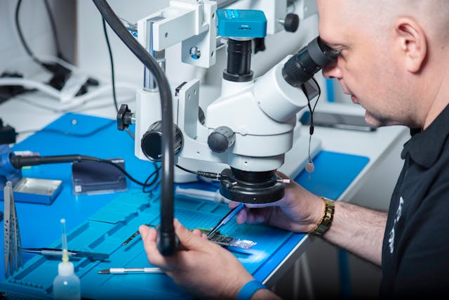 Technician inspecting a PCB under a microscope