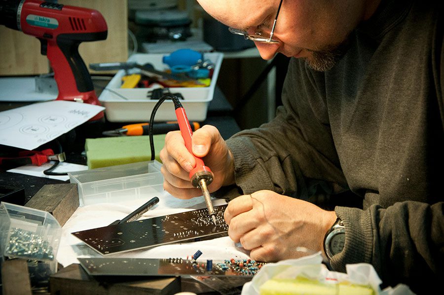 A man using a soldering iron on a device board.