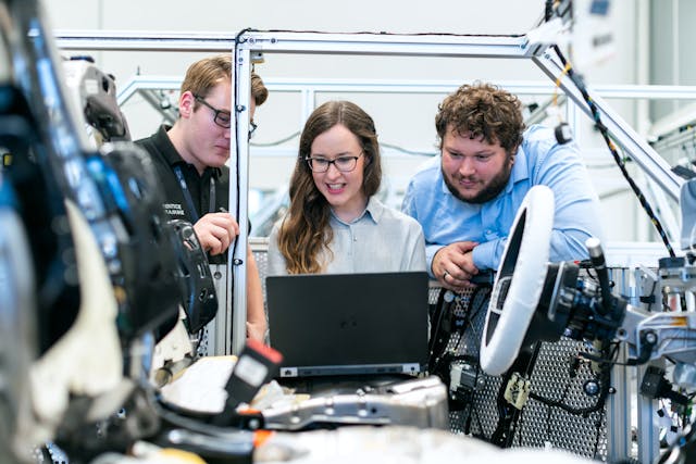 Engineers in a workshop staring at a laptop screen